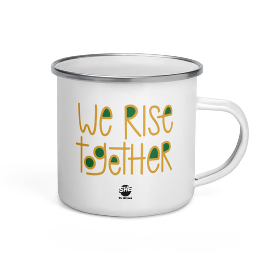 White enamel mug with a silver lip. Printed on the mug read "We rise together," in gold font with green filling in the spaces in the letters. Below the phrase is The SHE Mark logo in black, with "The SHE Mark" in black printed below the logo. This design is printed twice on the mug so it is visible regardless of which hand in which you hold the mug.
