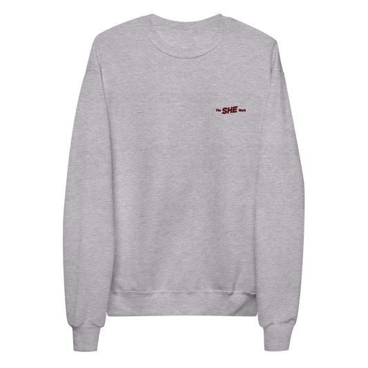 Grey crewneck sweatshirt with "the SHE Mark" embroidered on the left chest in black.