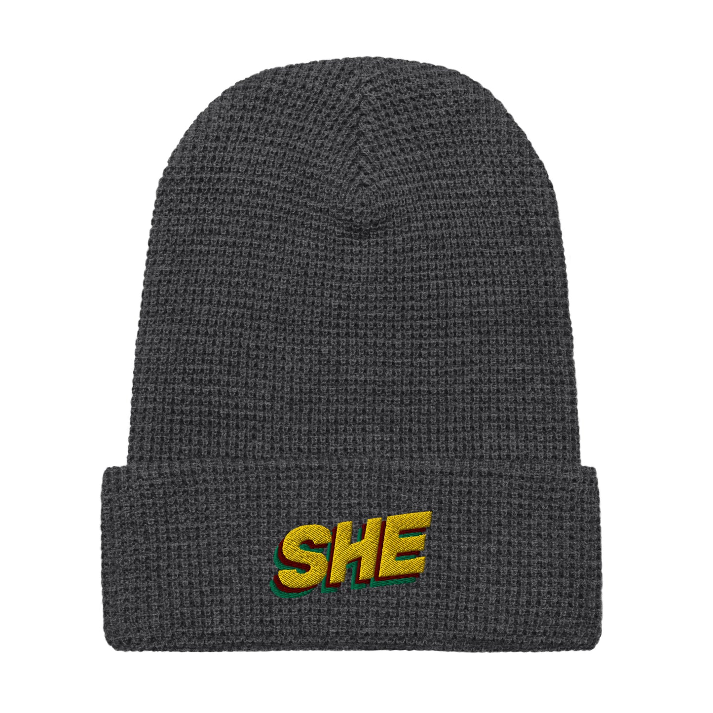 Darl grey waffle knit beanie hat with the word SHE embroidered on the front fold in the color gold, with a green and ruby shadow below it.